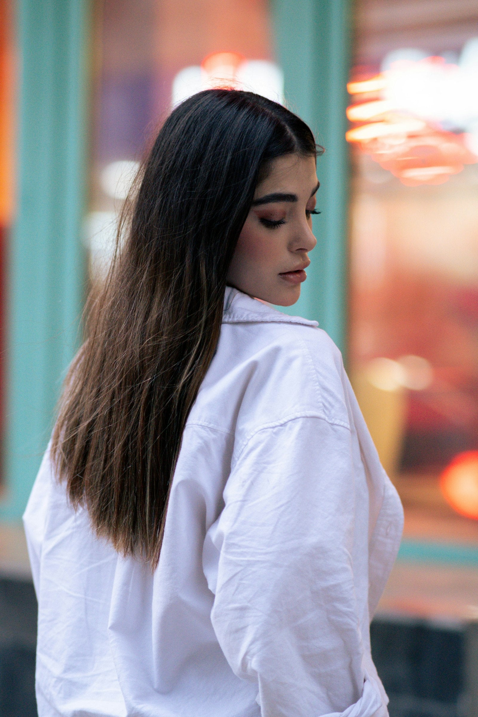 Donna con camicia bianca oversize in strada, luci calde
