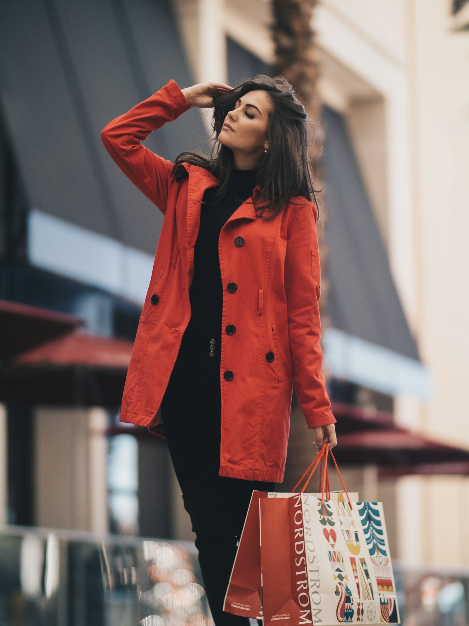 Donna con trench rosso e shopping bag in strada